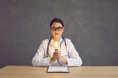 Portrait of thoughtful pensive young caucasian female doctor brainstorming looking at illuminated...