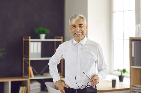 Portrait in the office of a successful happy senior European businessman or manager. Gray-haired...