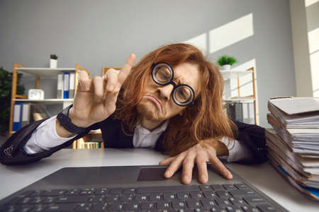 Unhappy tired man stuck at work and cant go home. Desperate employee sitting chained to laptop...
