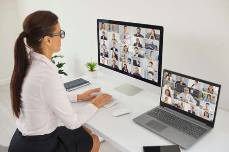 Company manager using two modern desktop and laptop computers for international business webinar or...