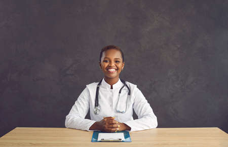Studio shot of female doctor with happy positive face expression. Pretty black woman in white...