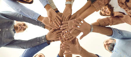Bottom view of a variety of happy men and women folding their arms together as a symbol of...