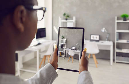 Black rental agent takes photo of apartment interior using smart tablet. Realtor video calling...