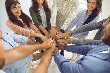 Team of happy male and female colleagues fold their arms together supporting each other. Top view of people folding their arms as a sign of teamwork. Concept of teamwork, support and joint efforts.の写真素材