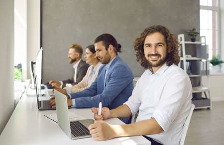 Group of business people working on modern desktop and laptop PCs. Portrait of happy handsome long...