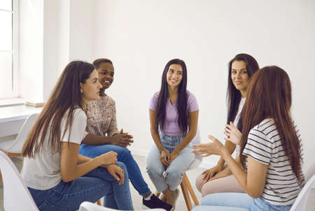 Psychological support. Group of young multinational women sit in a circle at a meeting of a womens...