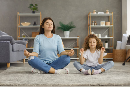 Calm young Caucasian mom and 7s daughter sit on floor with mudra hands meditate relieve negative emotions. Relaxed mother and small teen girl child rest practice yoga together. Stress free concept.の写真素材