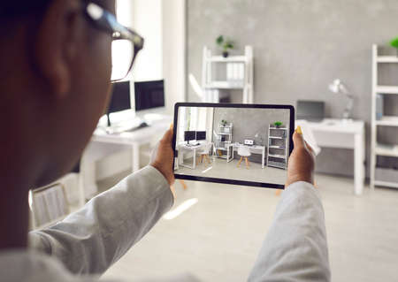 Black rental agent making photo presentation of apartment takes interior snaps using smart tablet...
