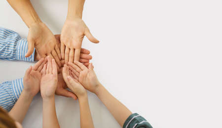 Young mother and father together holding hands of their little children in their open palms. Concept of family supporting, helping and caring about each other. Top view, close up, copyspace backgroundの写真素材