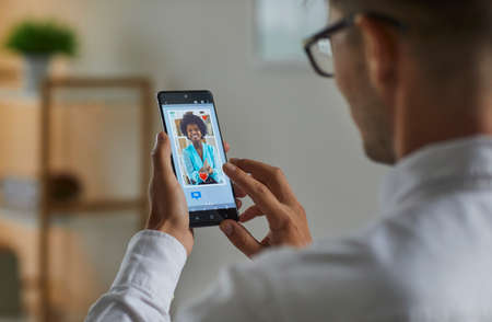 Single man flirting with beautiful woman on online dating app or website. Guy looking at mobile...