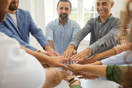 Team of happy positive senior and young business people standing around office table, smiling and...