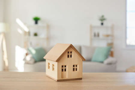 Close up of wooden house model on table in modern real estate agent office. Home building cottage maquette in realtor broker company. Bank property loan mortgage. Rent, realty concept.の写真素材