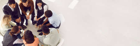 Copy space banner background with diverse team sitting in circle and talking. Psychologist providing professional guidance in group therapy. High angle view from above people in room with light floorの写真素材