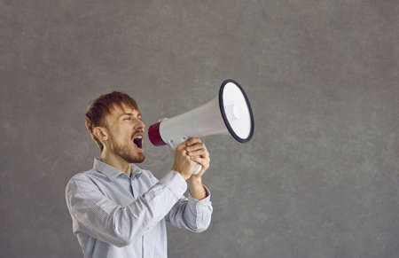 Portrait of man with megaphone drawing attention to something with his amplified voice. Young...