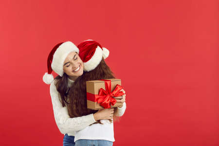 Happy family exchanging Christmas presents isolated on blank red text copyspace background. Studio...