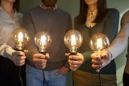 Creative minds developing collective innovative ideas. Team of people with bright glowing electric...