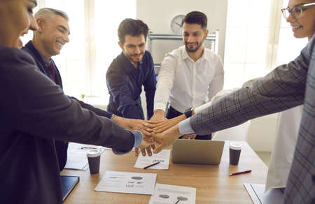 Successful team. Colleagues who are focused on successful work put their hands on each other as a...