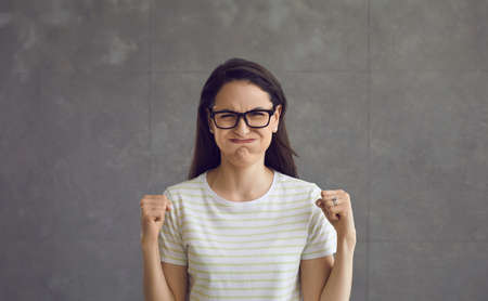 Woman puffed out her cheeks, rejoices, successful overcoming of difficulties. Beautiful woman, brunette in glasses, celebrating success, victory.の写真素材