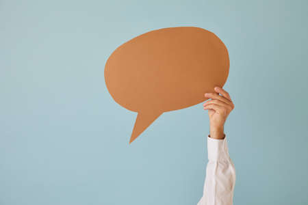 Close up man hand hold speech bubble on green studio background for message or vote. Male with empty blank copy space balloon expresser opinion give feedback. Recommend sale or promotion.の写真素材