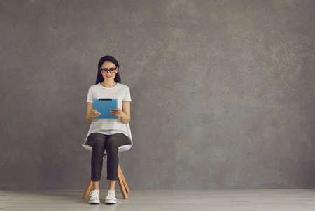 Woman is waiting for an interview, fills out a questionnaire. Woman with glasses sits on a chair and...