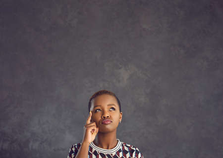 Studio portrait of serious confused undecided curious beautiful black woman isolated on copyspace...