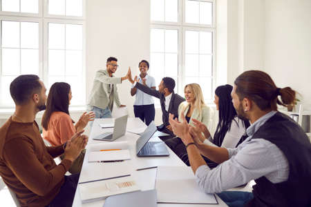 Happy business team celebrating good work results. Young ethnic man gives high five to colleague...