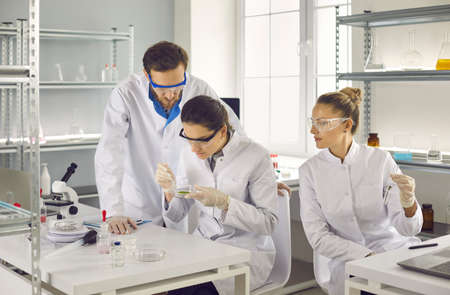 New discovery of scientists in the laboratory. Two women and a man conduct research using test tubes...