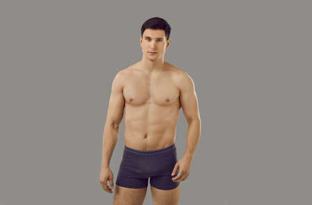 Portrait of muscular young Caucasian man in underwear pose on grey studio background advertise clothing. Toned sporty sexy male model in briefs for underclothing wear campaign. Sale, fashion concept.の写真素材