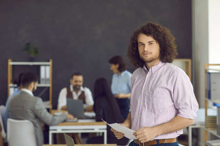 Portrait of a handsome stylish male employee standing in the office of a modern business center....