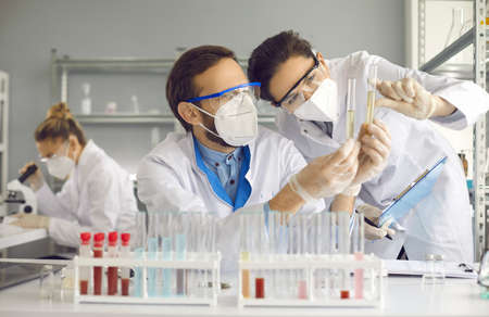 Scientists doing research in science laboratory. Medical chemists in white coats, gloves and glasses...