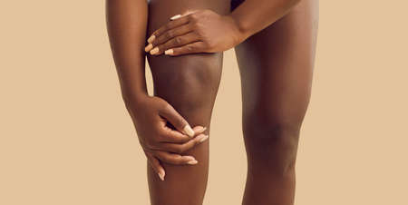 Crop close up of African American woman struggle with acute pain in kneecap. Pain in knee concept....