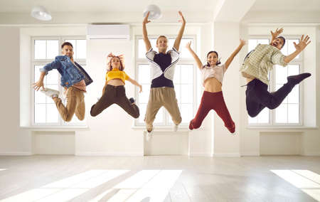 Happy contemporary dance crew jumping up in the air. Group of cheerful agile energetic young people...