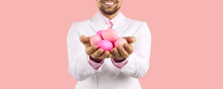 Cropped shot of a happy man smiling and holding a pile of beautiful traditional pink fresh Easter...