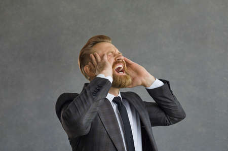 Crazy and angry Caucasian businessman in anger screams loudly and angrily grabbing his head. Man...
