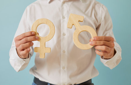 Close up of male and female gender symbols in human hands. Young man holding heterosexual couple symbols: Venus mirror and Mars arrow. Sexuality, attraction to opposite sex, love, relationship conceptの写真素材