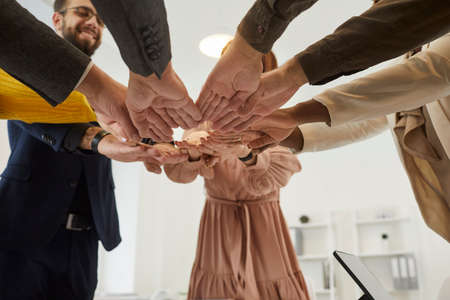 Happy diverse mixed race multiethnic business people join their hands as they gather together for a...
