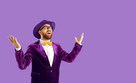 Wow, this is incredible. Studio portrait of funny surprised young man. Happy guy with ginger beard, wearing hat, suit, bow tie and glasses looking away at something with amazed expression on his faceの写真素材