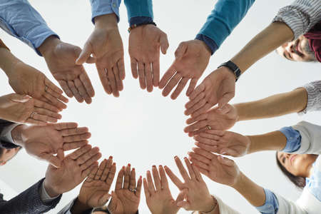 Team of people joining hands. Diverse group of business people standing in circle and putting their hands together. Shot from below, cropped shot, close up. Teamwork, unity, and partnership conceptsの写真素材