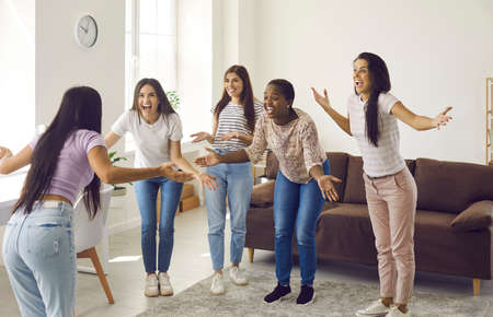Overjoyed diverse multiethnic young girls have fun play game at home together. Excited happy...
