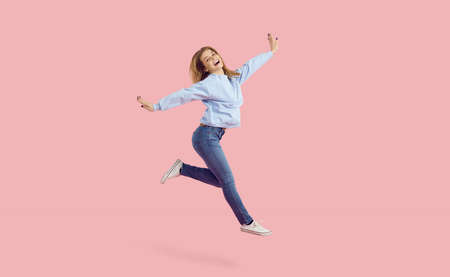 Happy cheerful ecstatic young woman dancing in the studio. Carefree pretty dancer girl wearing...