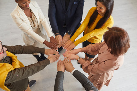 Diverse group of happy, smiling mixed race business people standing in a circle and putting their...