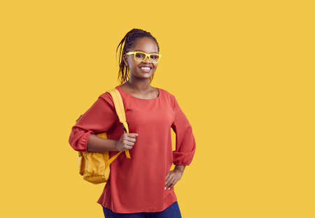 Portrait of smiling millennial African American girl student in glasses with backpack isolated on...