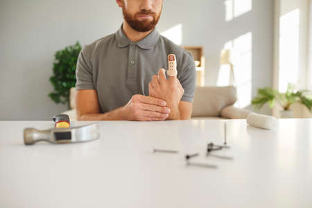 Close up of injured man hit finger with hammer have bandage for fast recovery. Male with splint or sling suffer from limb injury repair fix at home. Trauma and rehabilitation. Healthcare concept.の写真素材