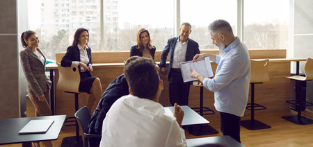 Team of people gather in modern office and have lesson with business teacher. Group of adult male...