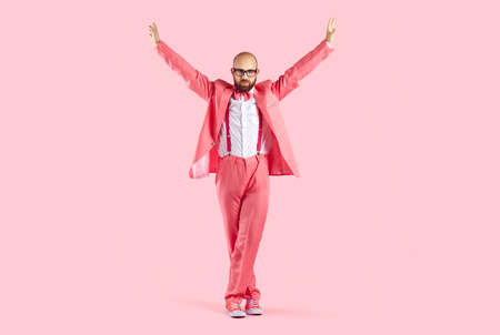 Happy disco man in pink costume isolated on studio background dancing relaxing. Funny male entertainer or performer in suit have fun enjoy party or celebration. Entertainment concept.の写真素材