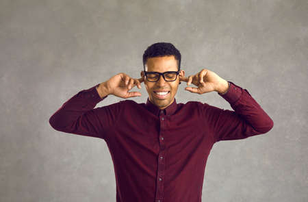 Ignorance is bliss. Peaceful pleased relieved man closes ears with fingers or plugs to keep mind clean, avoid listening to noise, dumb people, stupid comment or useless unsolicited uninvited criticismの写真素材