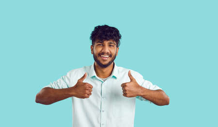 Studio shot of happy attractive bearded mustached young Indian man with curly black hair in smart...