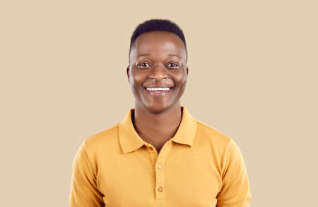Studio portrait of happy African American man. Cheerful joyful handsome young guy in polo shirt...