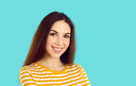 Headshot portrait of smiling young Caucasian woman isolated on blue studio background look at camera...