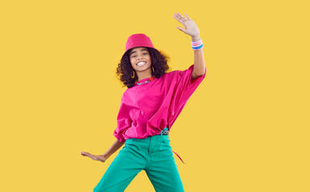 Happy joyful Black kid in funky outfit dancing in studio. Cheerful African dancer girl wearing loose...